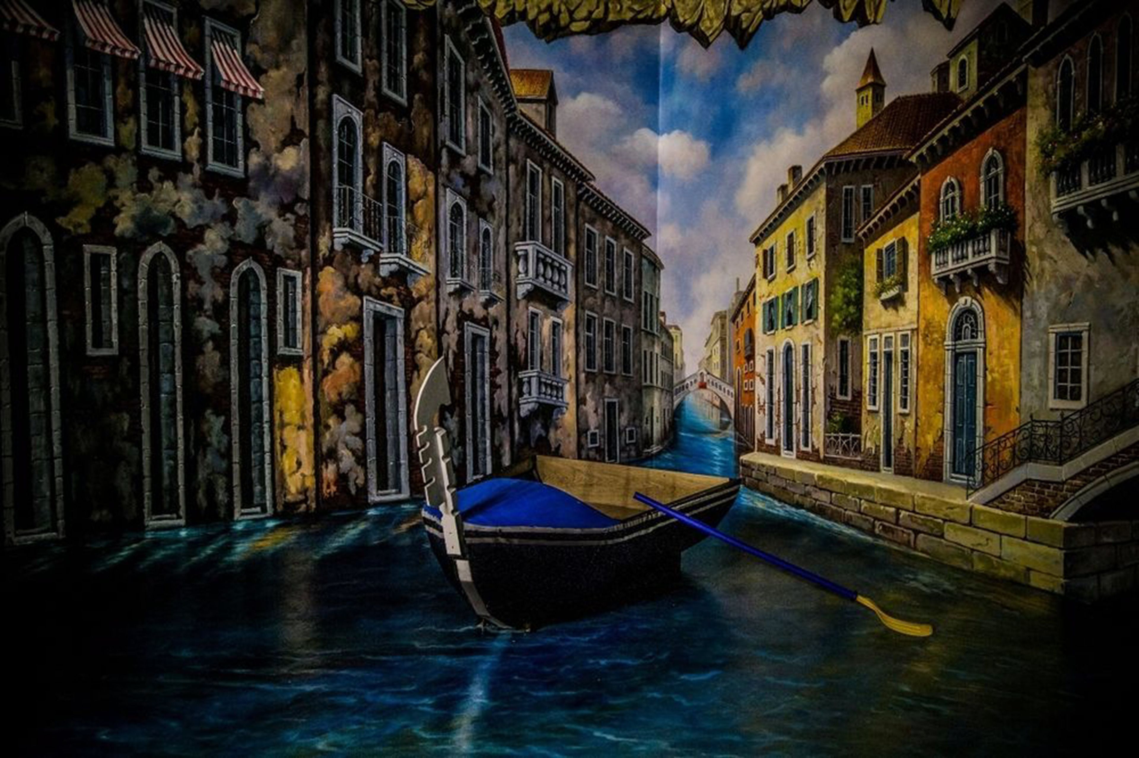 A canal scene with buildings on either side and a gondola in the water.
