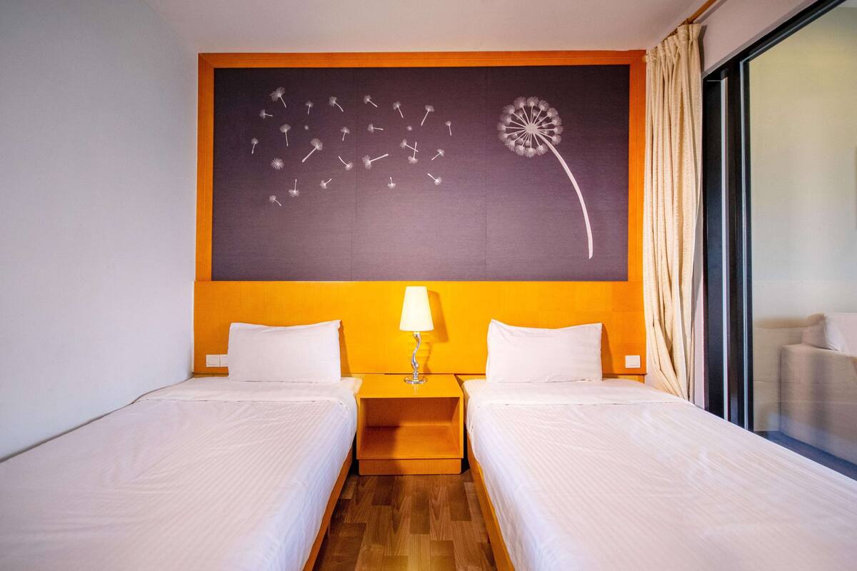 Quarto de hotel com duas camas, uma janela grande e uma pintura de esfinge.