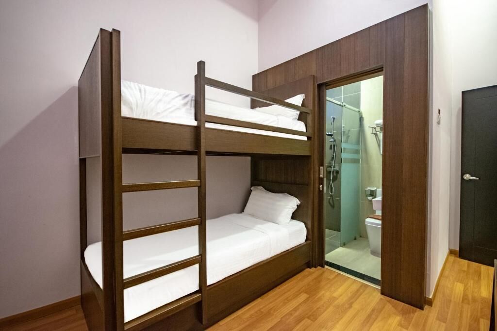 A bunk bed room with a wooden frame, white bedding, and a wooden floor.