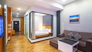 Een moderne hotelkamer met een glazen bed, een sofa, een salontafel en een schilderij aan de muur.