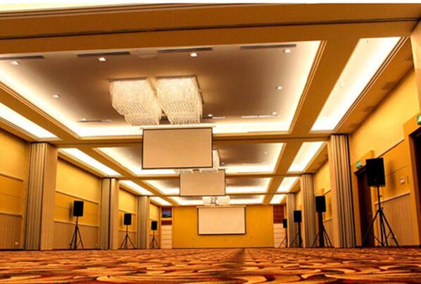 Un salón de conferencias de hotel con piso alfombrado, luces de techo y sistemas de sonido.