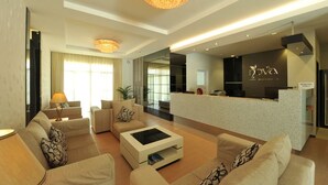 Een moderne hotel lobby met een receptiebalie, banken en een kroonluchter.