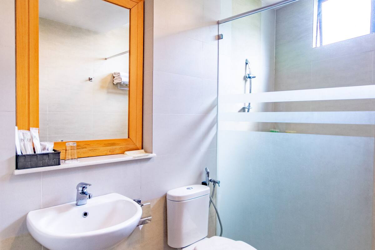 Uma casa de banho moderna com uma pia, sanita e chuveiro brancos.