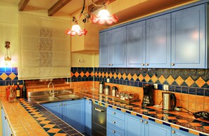 A kitchen with blue cabinets, a tiled backsplash, and a sink.