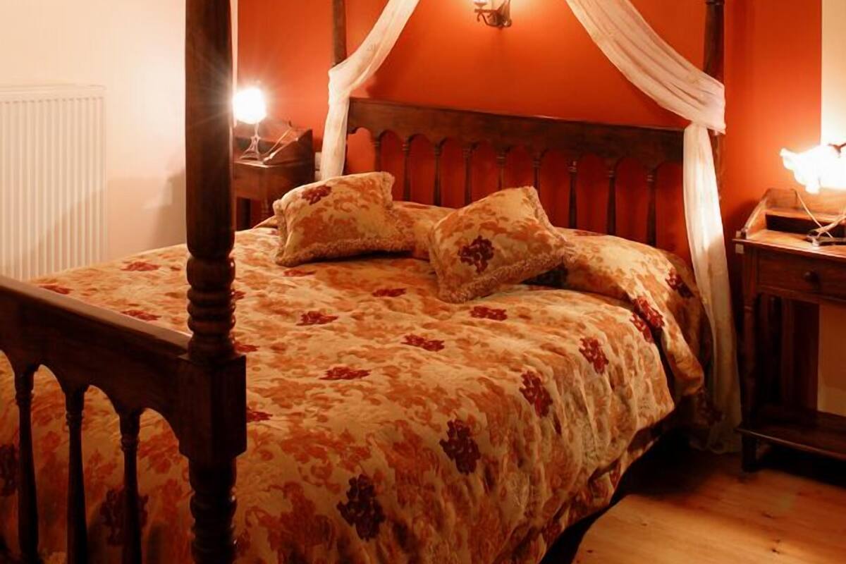 Quarto com cama de dossel, teto de madeira e um dossel.