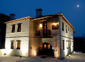 Ein Steinhaus mit Balkon, Bogenportal und mehreren Schornsteinen.
