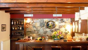Eine Bar mit einer Steinwand, Holzbalkendecke und Regalen voller Flaschen und Gläser.