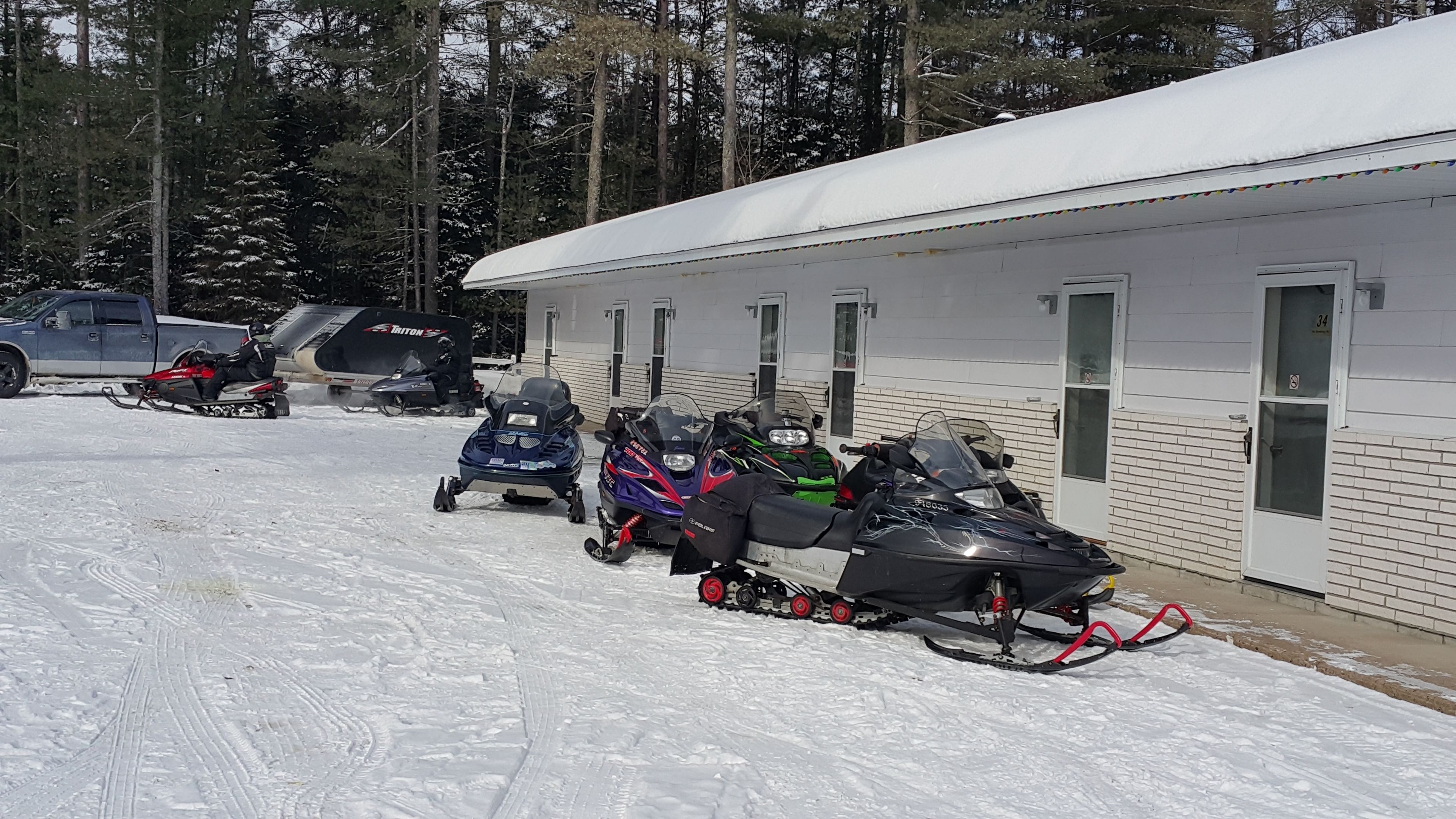 A snowmobile storage area with several snowmobiles parked in front of a building.