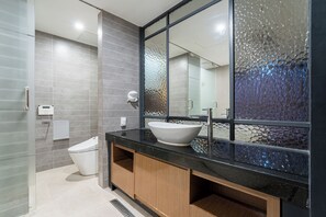 A modern bathroom with a large mirror, a white sink, and a glass shower enclosure.