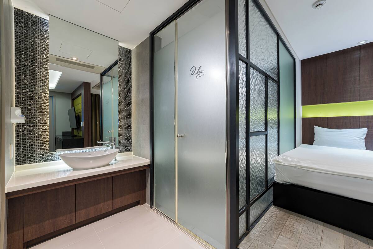 A modern bathroom with a large mirror, a vessel sink, and a walk-in closet with a sliding door.