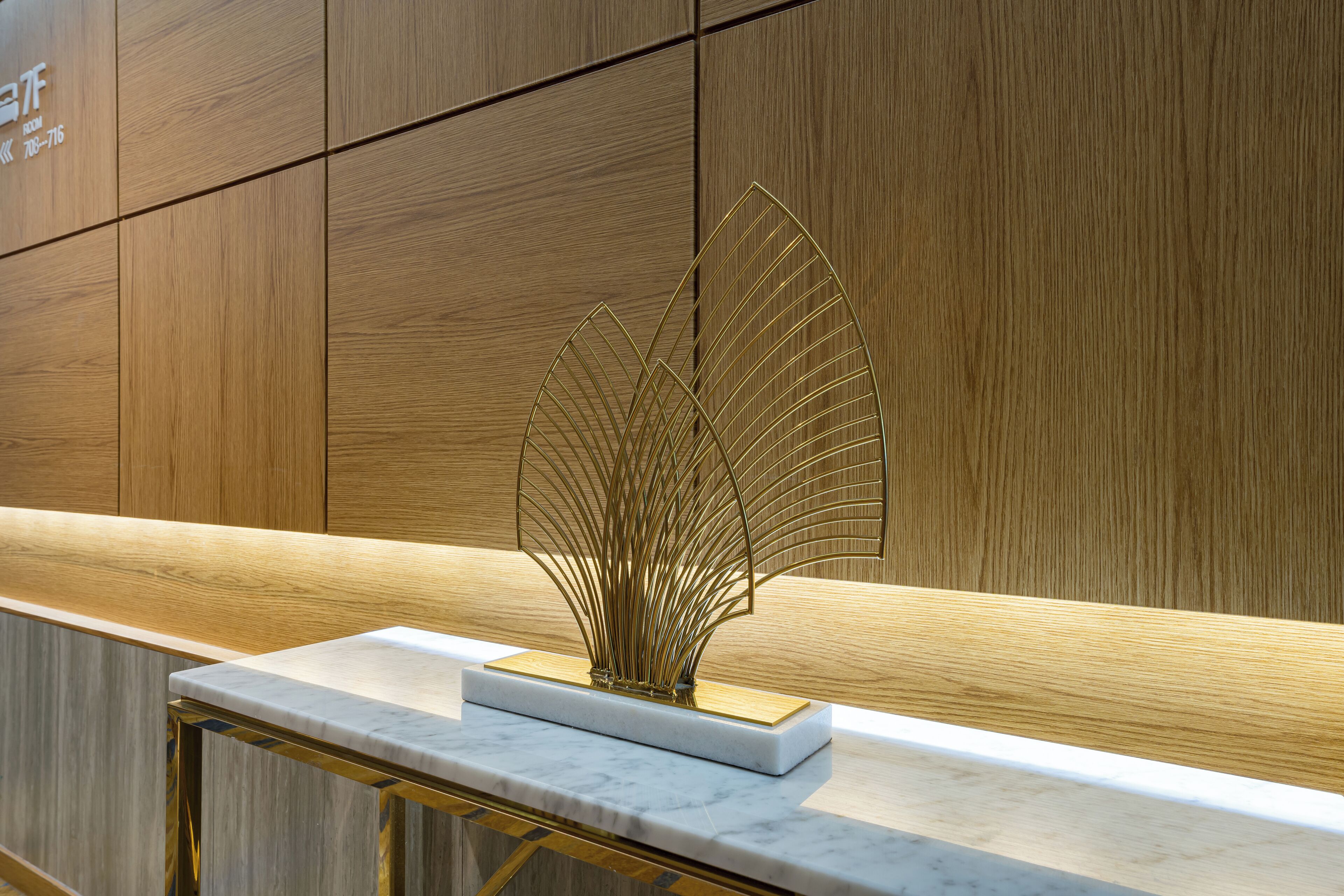 Una encimera de mármol con un detalle decorativo dorado y un panel de pared de madera.
