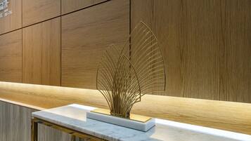 Una encimera de mármol con un detalle decorativo dorado y un panel de pared de madera.