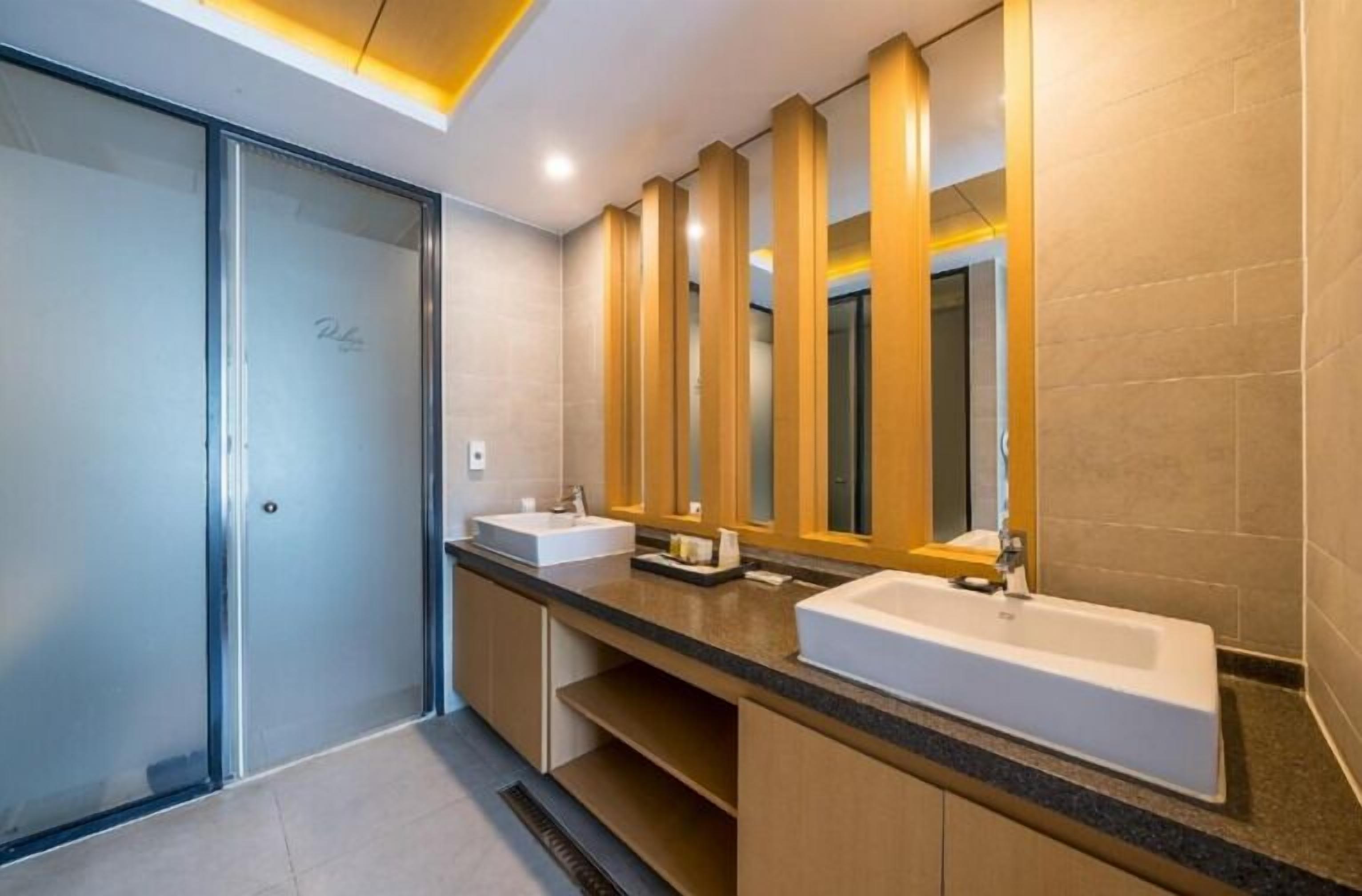 A modern bathroom with two sinks, a large mirror, and wooden accents.