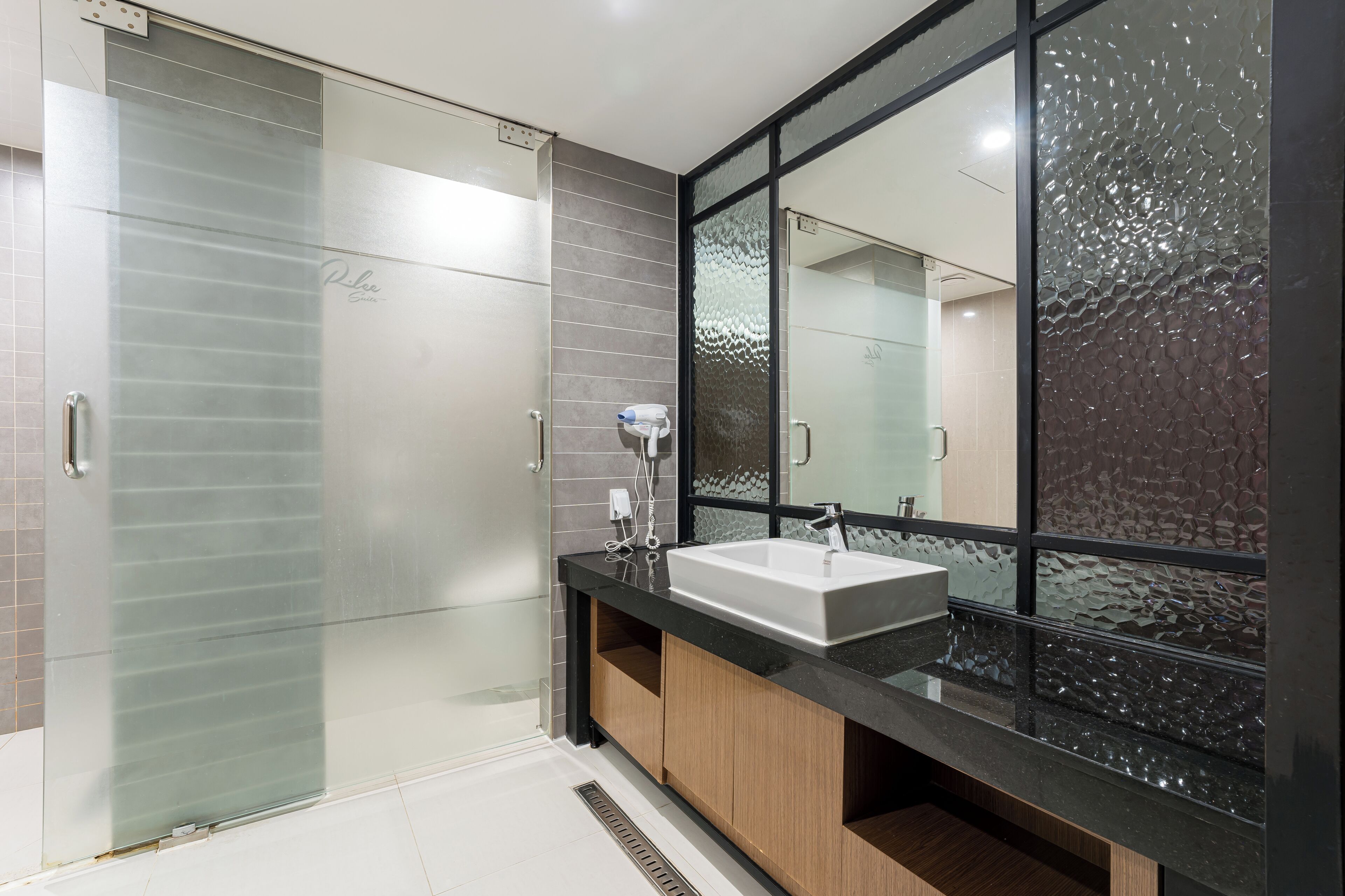 A modern bathroom with a glass shower enclosure, a large mirror, and a vanity with a sink.