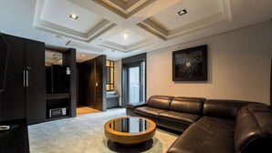 Un salon moderne avec un canapé en cuir, une table basse ronde et une grande fenêtre laissant entrer la lumière naturelle.