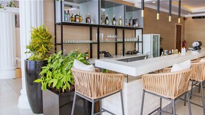 A bar area with a long counter, wicker chairs, a large potted plant, and a glass display case with bottles.