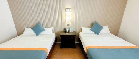 Habitación de hotel con dos camas, una mesita de noche, un teléfono y una lámpara fijada a la pared.