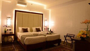 A hotel room with a large bed, bedside tables, a desk, and a chair.