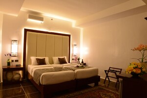 A hotel room with a large bed, bedside tables, a desk, and a chair.