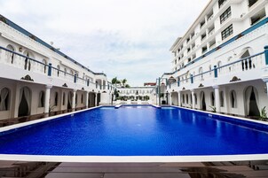 Una amplia piscina interior de diseño simétrico, rodeada de edificios blancos con ventanas y balcones arqueados.