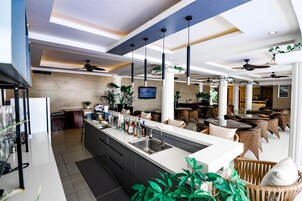 Cocina moderna con una isla central, zona de bar y comedor con mobiliario de mimbre.