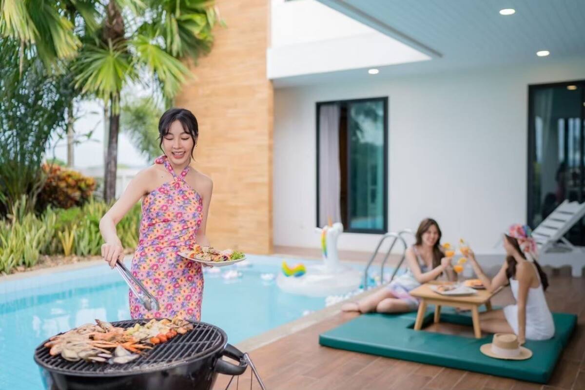 A poolside area with a grill, lounge chairs, and a dining table.