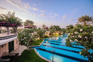 A swimming pool with a blue and white striped pattern, surrounded by lush greenery and palm trees. - The Sea-Cret Garden Hua Hin (Hua Hin)