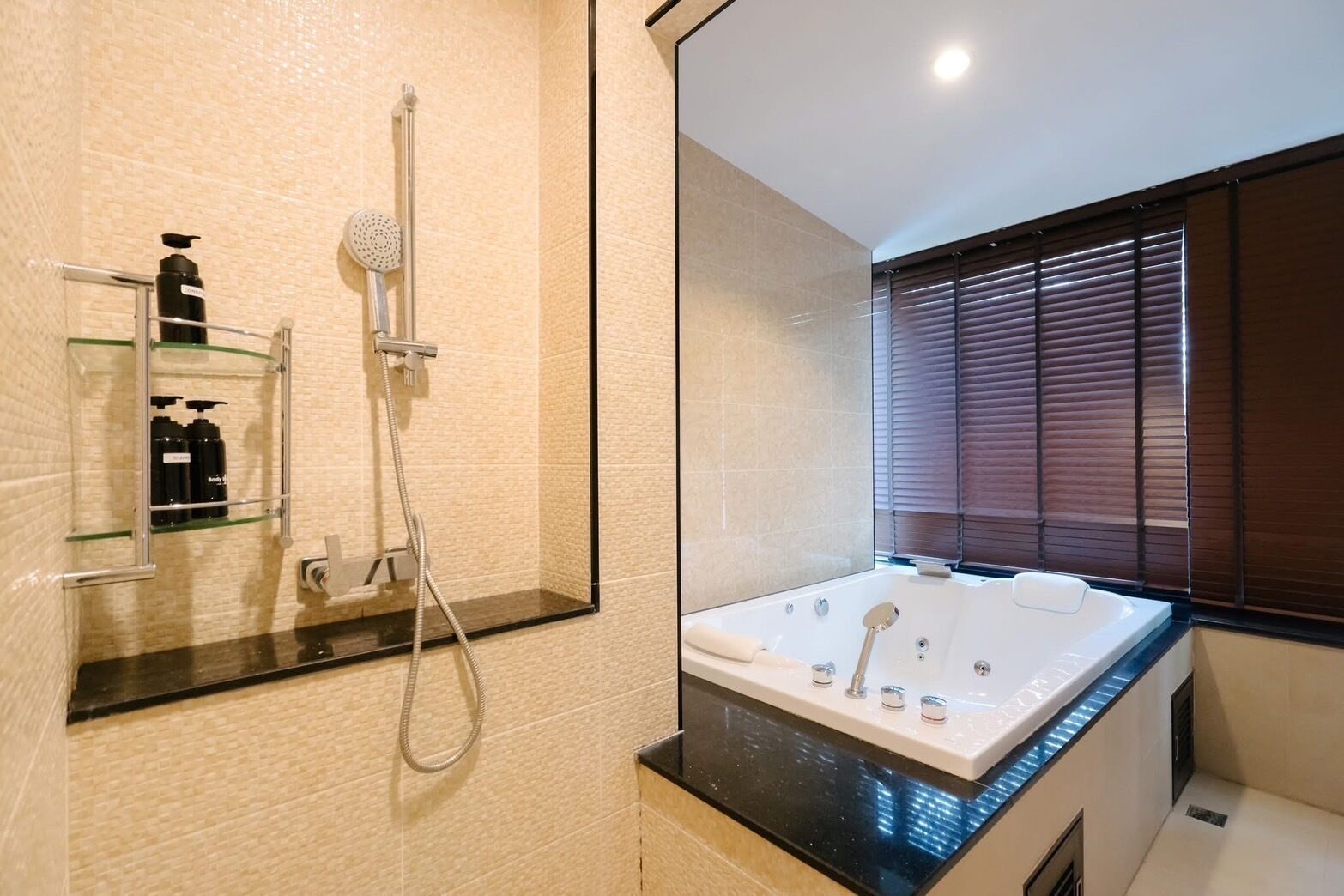 A modern bathroom with a glass-enclosed shower, a large bathtub, and a window with blinds.