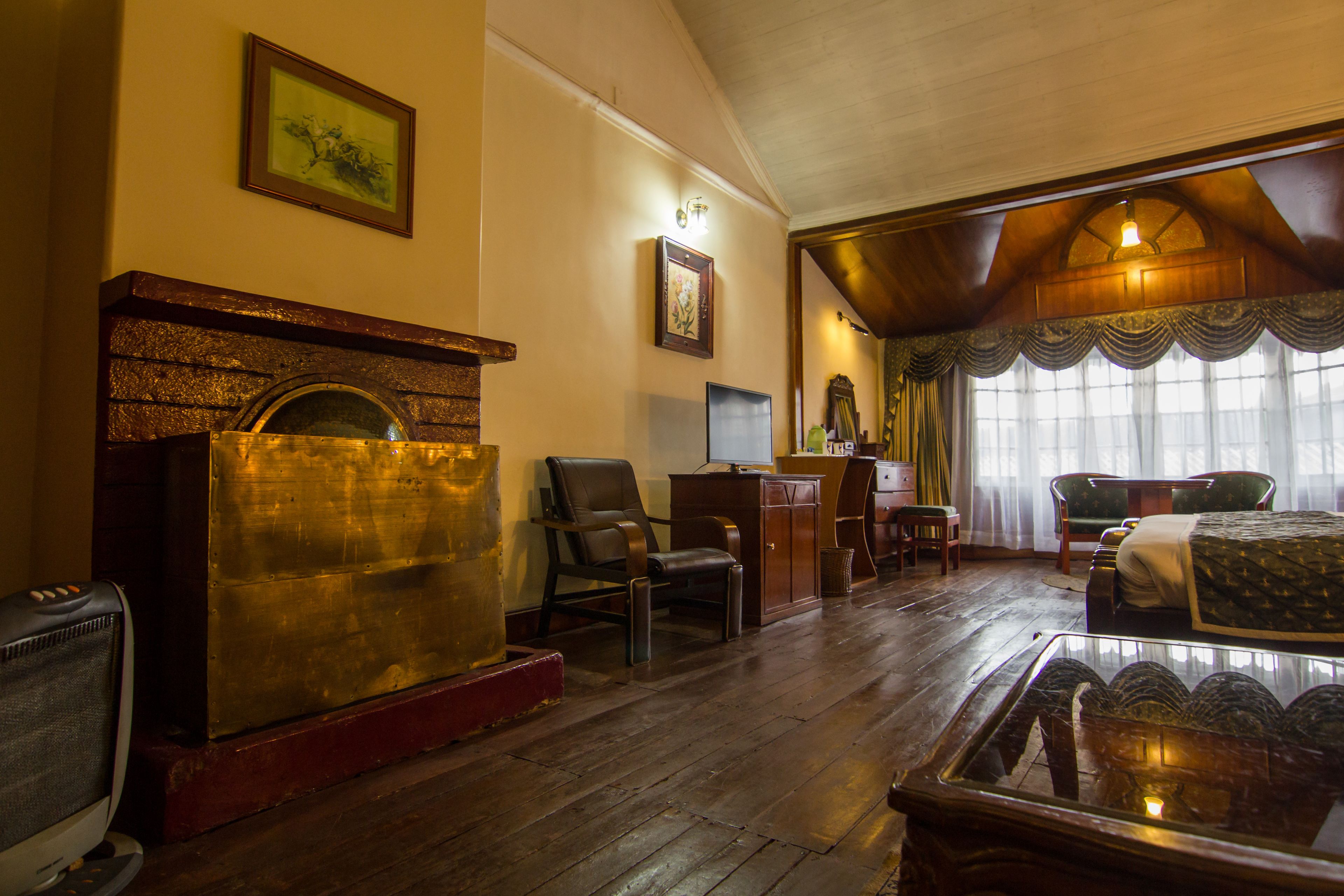 Una habitación tradicional con chimenea, muebles de madera y un gran ventanal con cortinas.