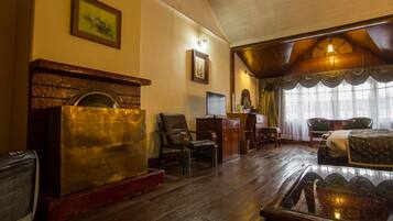 Una habitación tradicional con chimenea, muebles de madera y un gran ventanal con cortinas.