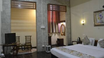 A hotel room with a bed, a desk with a chair, a television, and a mirror.
