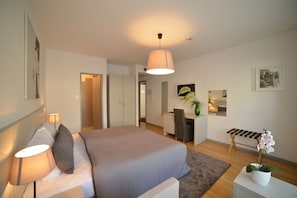 A modern bedroom with a bed, bedside lamps, a desk, and a chair. - Hotel Garden (Zagreb)