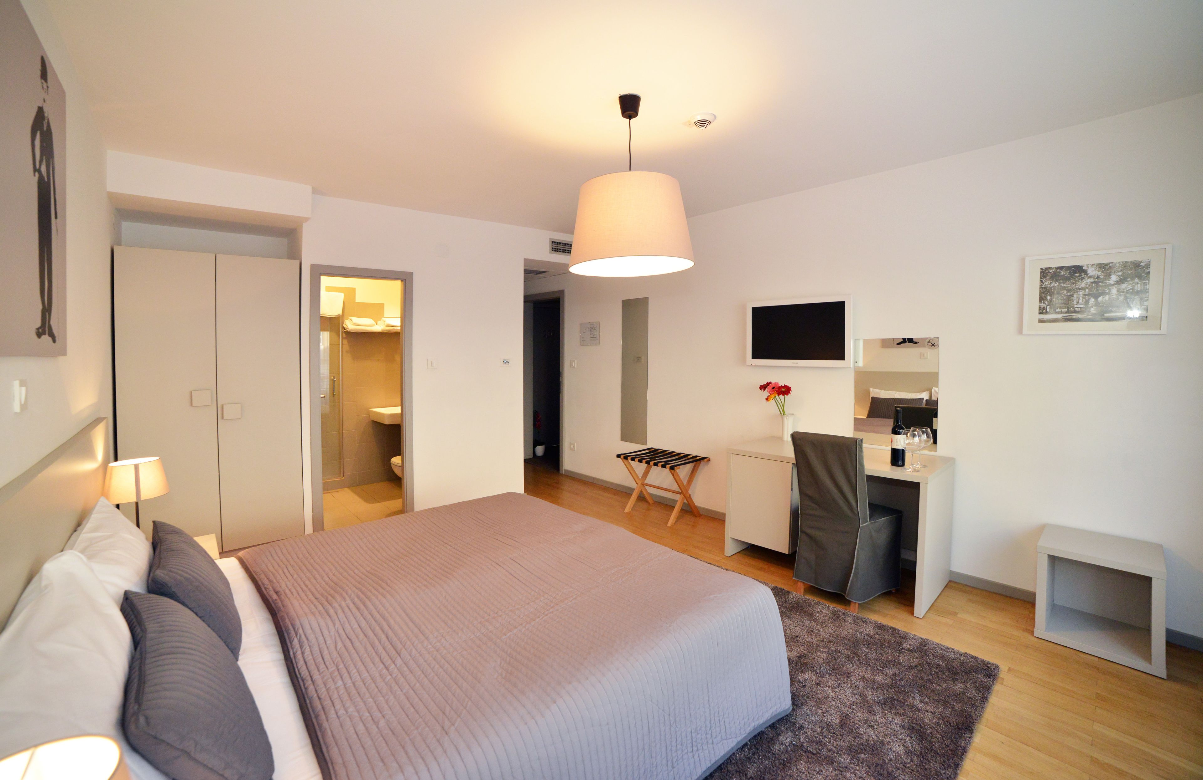 A modern bedroom with a bed, desk, and a small seating area.