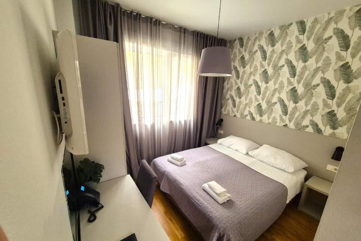 Ein Hotelzimmer mit Bett, Schreibtisch, Telefon und einem Fenster mit Vorhängen.
