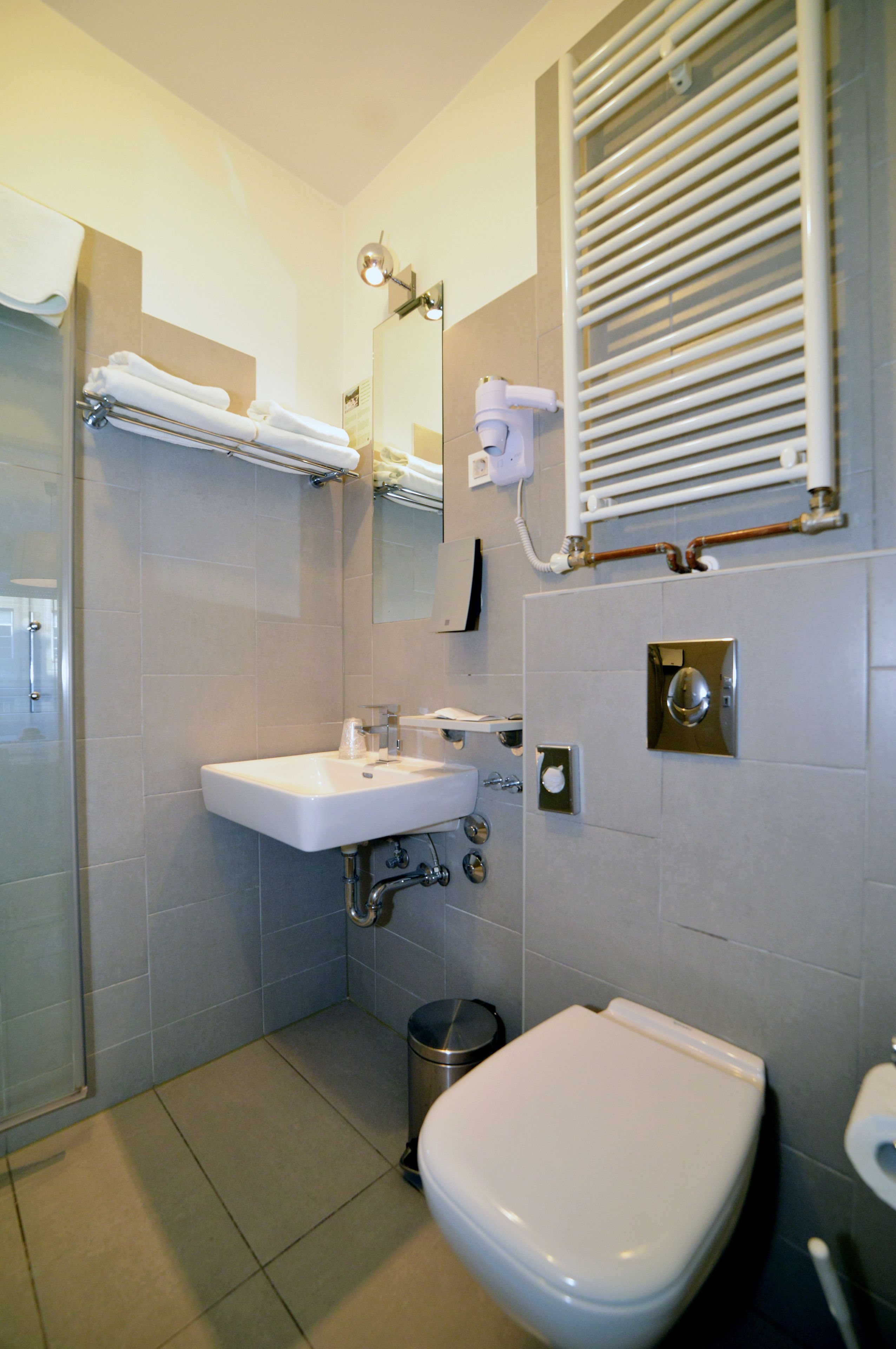 A modern bathroom with a white sink, a toilet, a mirror, and a towel rack.