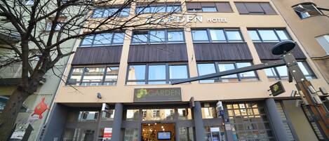 En byggnad med flera våningar, och en skylt som visar texten ”Garden Hotel”.