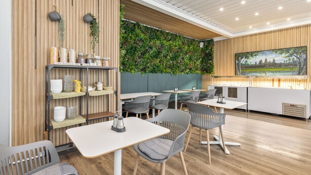 Un interior de restaurante con paneles de madera, decoración mural verde y un cuadro grande de un templo.