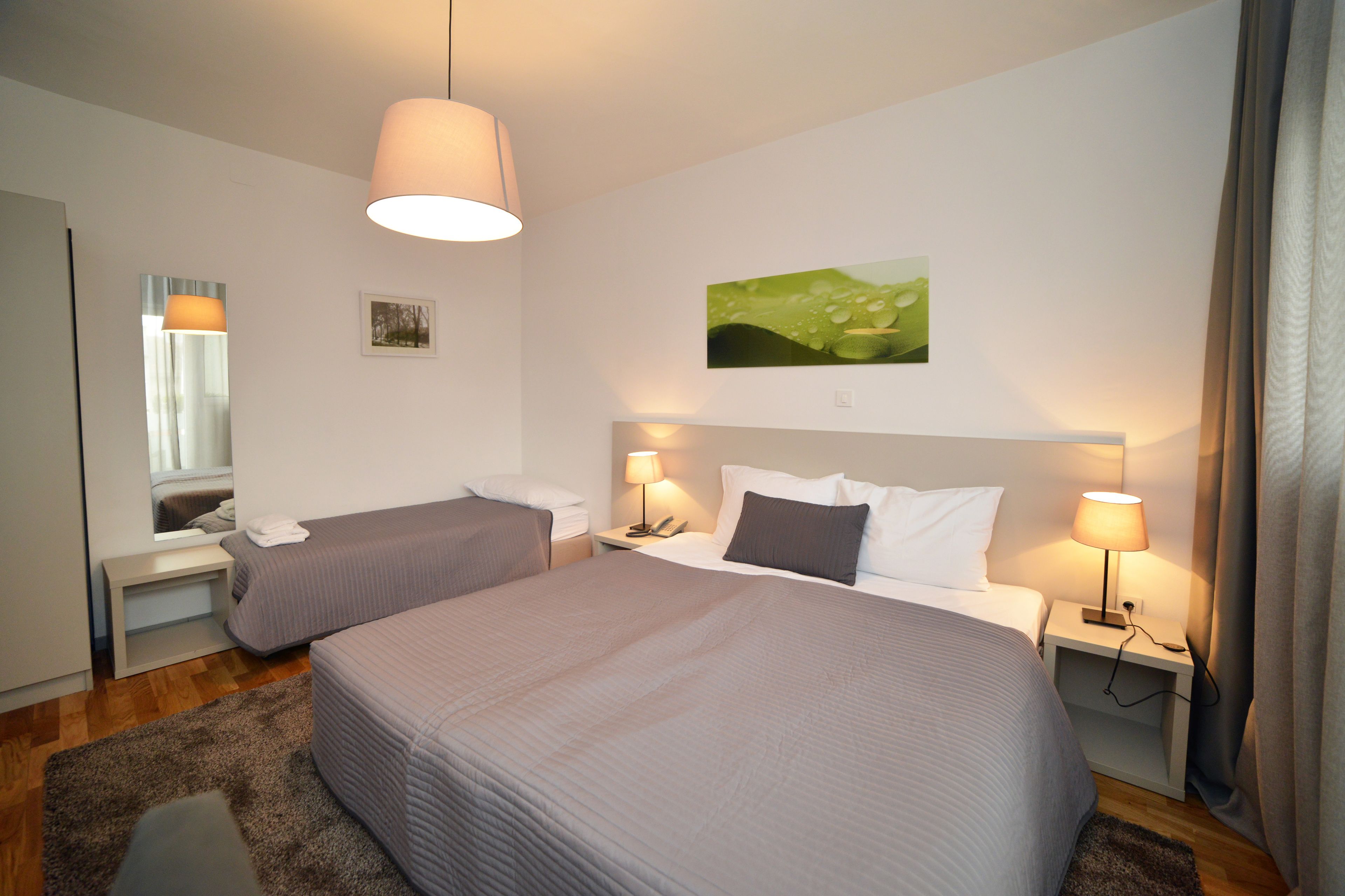 Habitaci ón de hotel con dos camas, un ventanal grande, un cuadro y una lámpara.