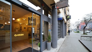 Un hotel moderno con un letrero que dice 'GARDEN', ventanas amplias y un interior visible con una araña.