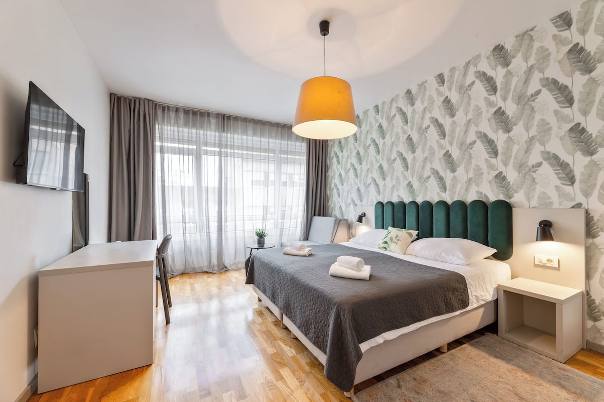 Ein modernes Schlafzimmer mit einem Bett, Nachttischen, einem Schreibtisch und einem Fernseher.
