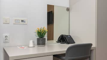 A modern office space with a desk, chair, telephone, and a potted plant.