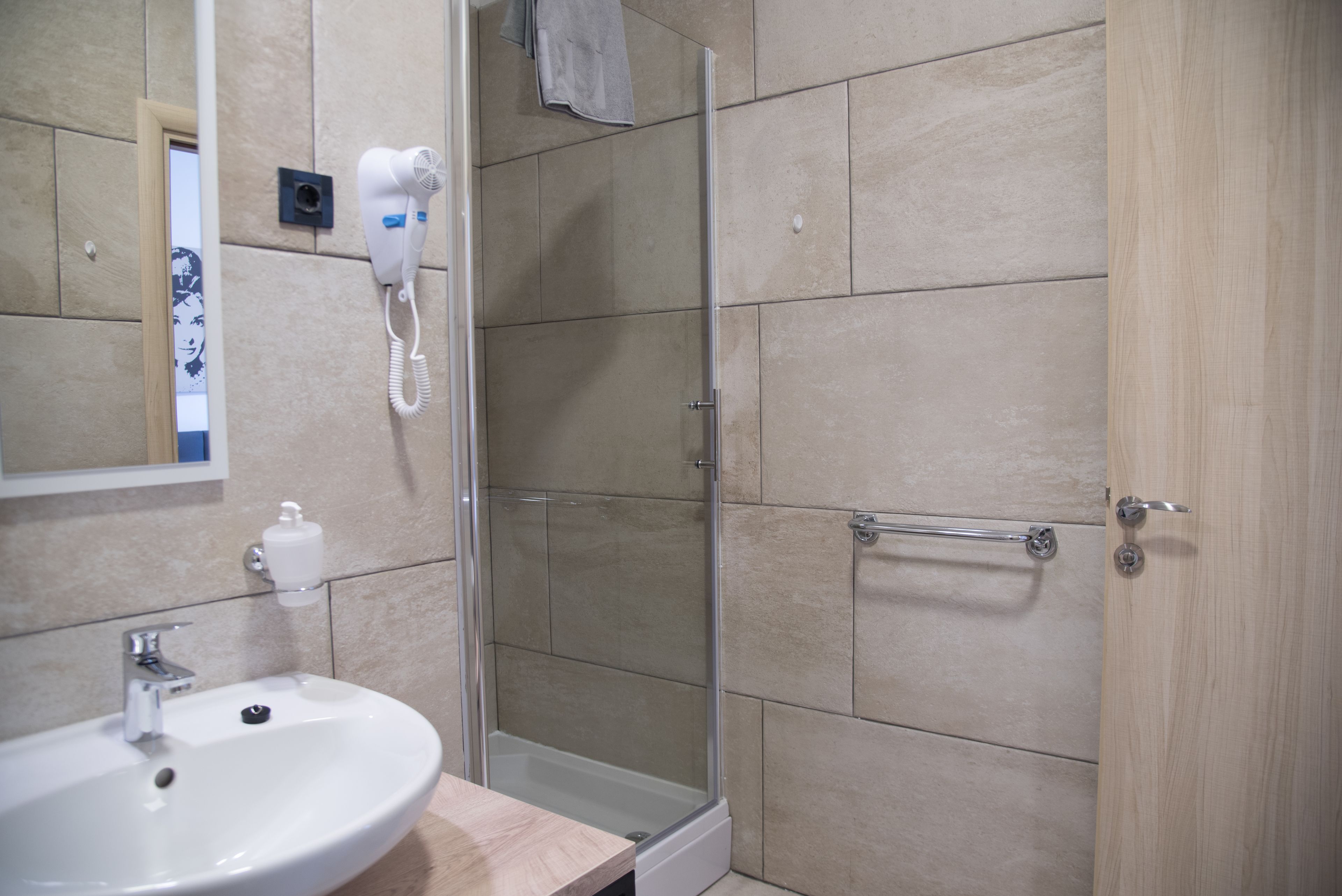 Une salle de bain équipée d’un lavabo, d’un miroir, d’un sèche-cheveux et d’une douche.