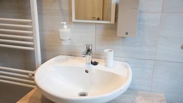Un bagno con un lavandino bianco, uno specchio e un porta asciugamani.