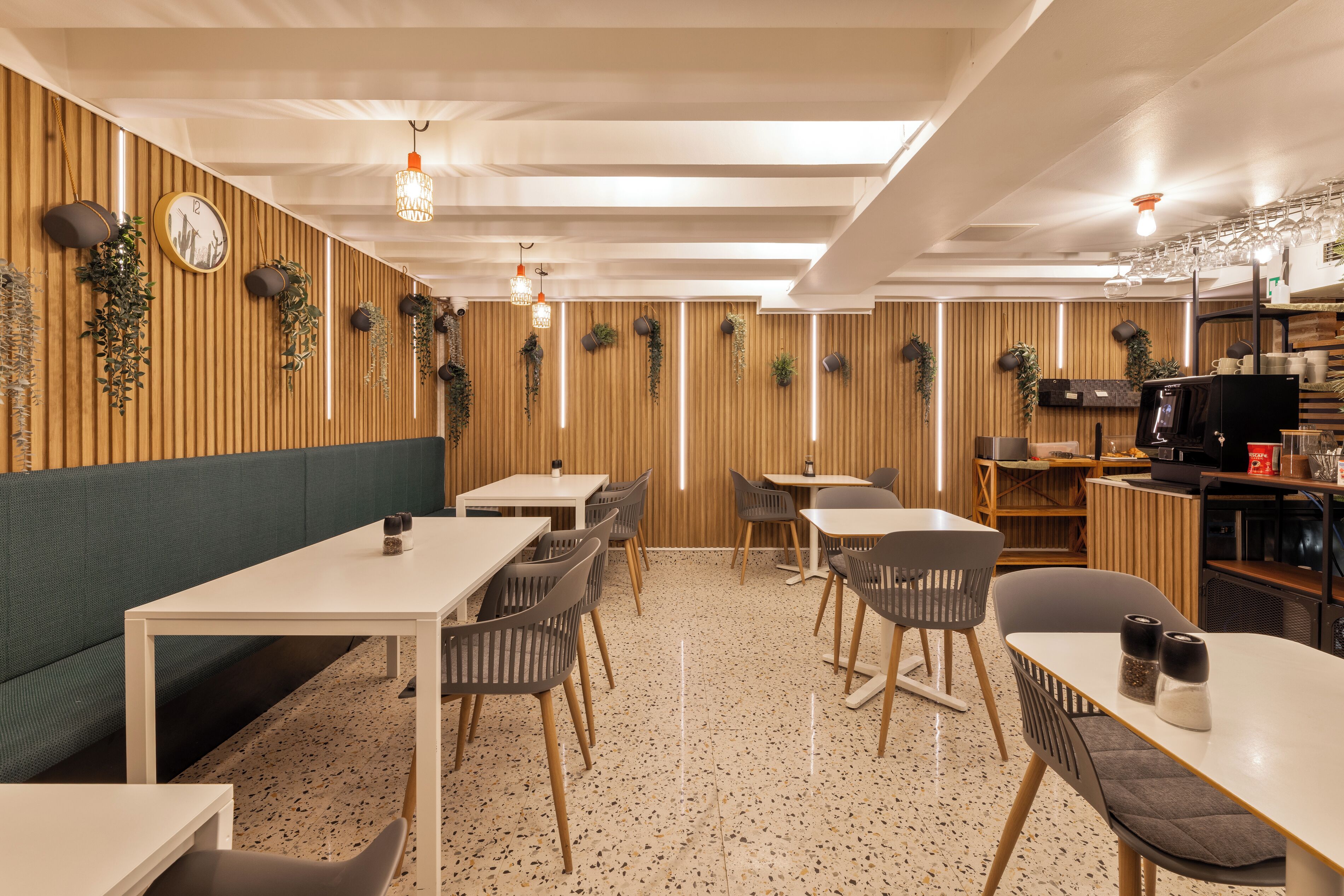 Interior de restaurante con paredes de paneles de madera, varios arreglos de asientos e iluminación colgante.