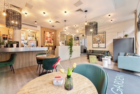 A modern interior with a bar area, seating, and a 'GARDEN' sign on the floor.. Hotel Garden