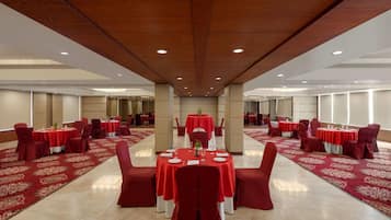 Un salón de banquetes con mesas redondas, manteles y sillas rojas a juego.