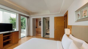 Quarto de hotel moderno com uma cama grande, televisão de tela plana, mobiliário de madeira e porta de vidro que dá para uma varanda.