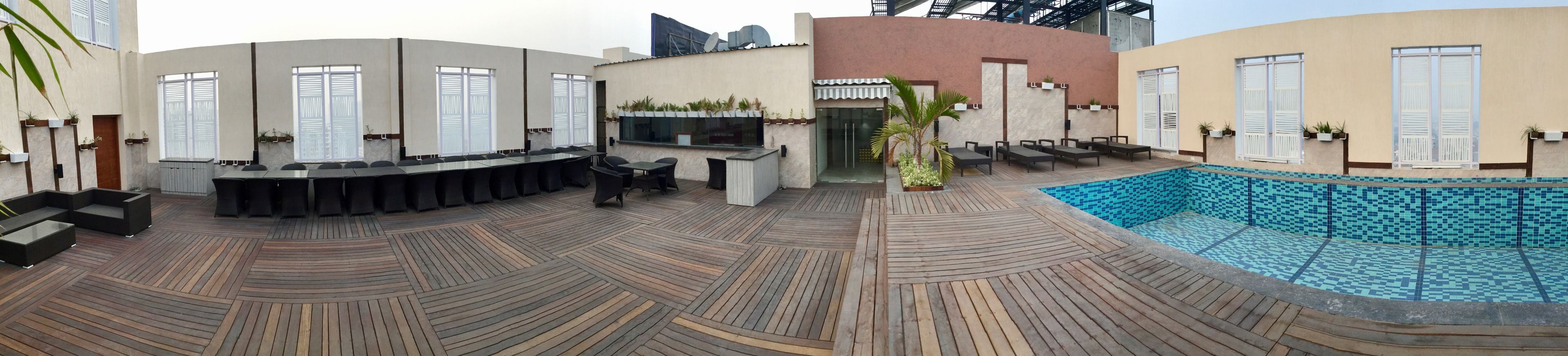 Un bar en la azotea con piscina, mesas al aire libre y un diseño arquitectónico moderno.