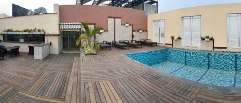 Un bar sul tetto con piscina, posti a sedere all'aperto e un design architettonico moderno.