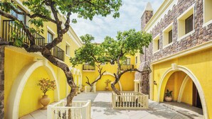 Un patio con paredes amarillas, barandillas blancas y un árbol en el centro.